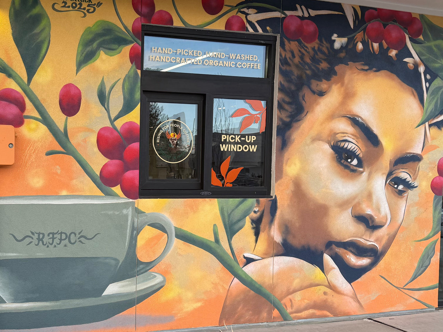 Mural on a building exterior with coffee-themed design and woman's face.